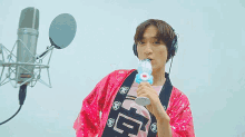 a man wearing headphones and a pink sequined jacket is holding a toy in his hand .