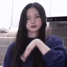 a woman with long hair is making a heart shape with her hands .