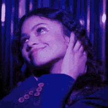 a close up of a woman 's face in a dark room with purple lights .