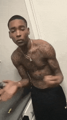 a shirtless man with tattoos on his arms is standing in front of a mirror .