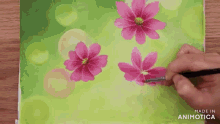 a person is painting pink flowers on a green background .
