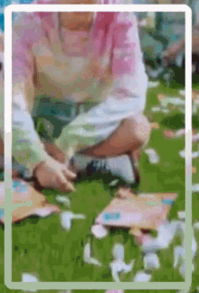 a blurry picture of a person sitting on the grass with petals .