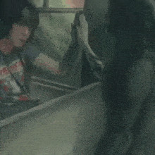 a man wearing a t-shirt that says iron maiden talks to another man