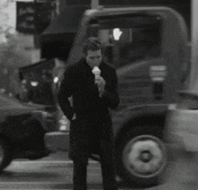 a man in a black coat eating an ice cream cone