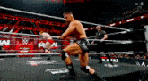 two men are wrestling in a wrestling ring while a referee looks on .