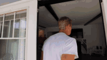 a man in a white shirt is standing in front of a sliding glass door
