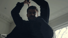 a man in a suit is holding a knife in a dark room with an amazon prime arrow in the corner