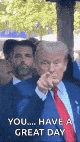 a man in a suit and tie is pointing at the camera .
