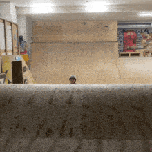 a person wearing a helmet stands in front of a wooden wall with graffiti on it