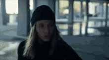 a woman is wearing a black hat and a black jacket .