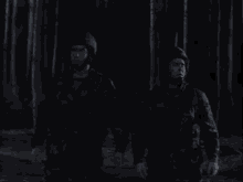 two men in military uniforms are standing in the woods