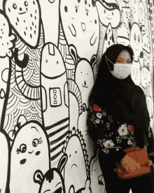 a woman wearing a face mask is standing in front of a wall with drawings on it and the word boo on it