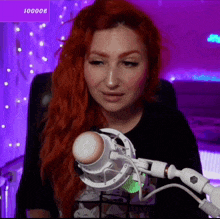 a woman with red hair is sitting in front of a microphone with a purple background and the number 100008 on the bottom