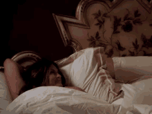 a woman is laying in a bed with a floral headboard