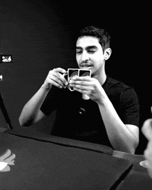 a man in a black shirt is holding a playing card with a sticker on it that says 30