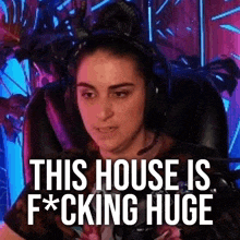 a woman wearing headphones is sitting in a chair with the words `` this house is fucking huge '' written on the screen .