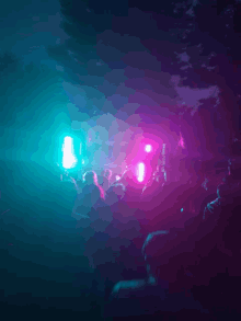 a crowd of people are gathered in a dark room with purple and blue lights