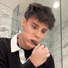 a young man brushing his teeth with a black toothbrush