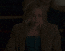 a woman in a brown jacket is smiling in a dark room