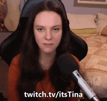 a woman is sitting in front of a microphone with the words twitch.tv/itstina written below her