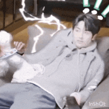 a man is laying on a couch with a white dog behind him .