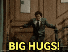 a man in a suit and tie is standing on a set of stairs with the words big hugs written in yellow