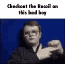 a man wearing glasses is pointing at the camera with the words `` checkout the recoil on this bad boy '' .