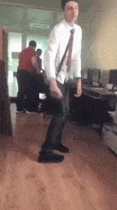 a man in a tie is dancing in an office