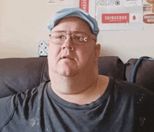 a man wearing glasses and a hat is sitting on a couch