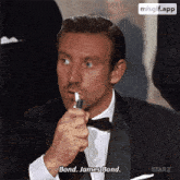 a man in a tuxedo is lighting a cigarette and saying bond james bond