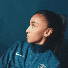 a woman wearing a blue nike jacket with the word paris on the front