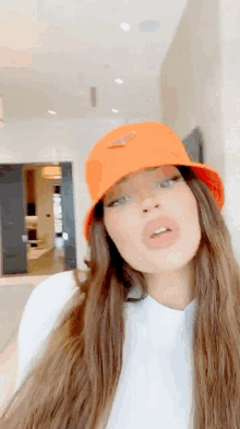a woman wearing an orange hat with a prada logo