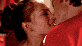 a man and a woman are kissing in a red shirt