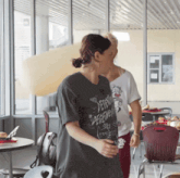 a woman wearing a t-shirt that says " attention degenerate " stands next to another woman