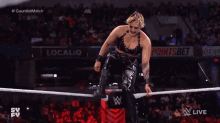 a wrestler is kneeling down in a wrestling ring while another wrestler is jumping over him .