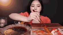 a woman eating food with chopsticks and a plate that says ' dinner ' on the bottom