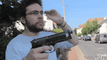 a man is holding a gun in front of a sign that says gifru.com