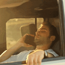 a man talking on a cell phone while sitting in a car