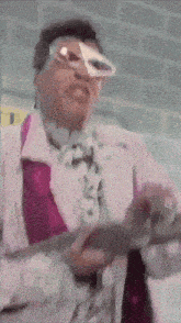 a man wearing glasses and a purple tie is standing in front of a wall