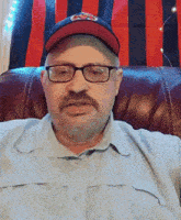 a man wearing glasses and a baseball cap with a cardinals logo on it