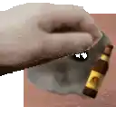 a hand is holding a bottle of beer next to a skull on a table .