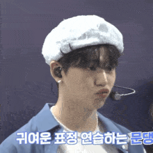 a man wearing a white hat and a blue shirt has korean writing on his shirt