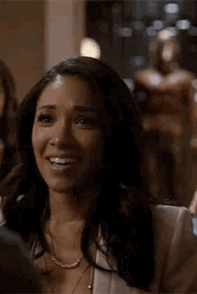 a woman is smiling and looking at the camera while sitting in front of a statue of iron man .