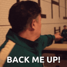 a man in a green jacket with the words back me up on his back