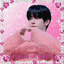 a picture of seungho de andrea making a heart shape with his hands