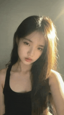 a woman with long hair is wearing a black tank top .