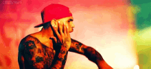 a man with a lot of tattoos is wearing a red hat .