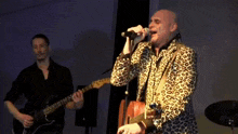 a man playing a guitar and singing into a microphone