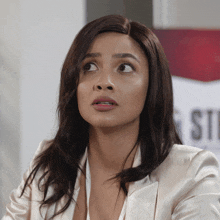 a woman with a surprised look on her face stands in front of a sign that says st
