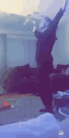 a man is dancing in a living room with his arms in the air